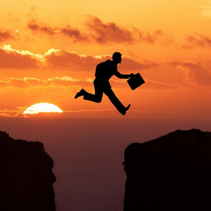 Silhouette of a man jumping over a gap between land. Meant to illustrate Power, Strength and Boldness in God