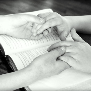 Holding hands across the bible. Meant to illustrate prayer & asking God