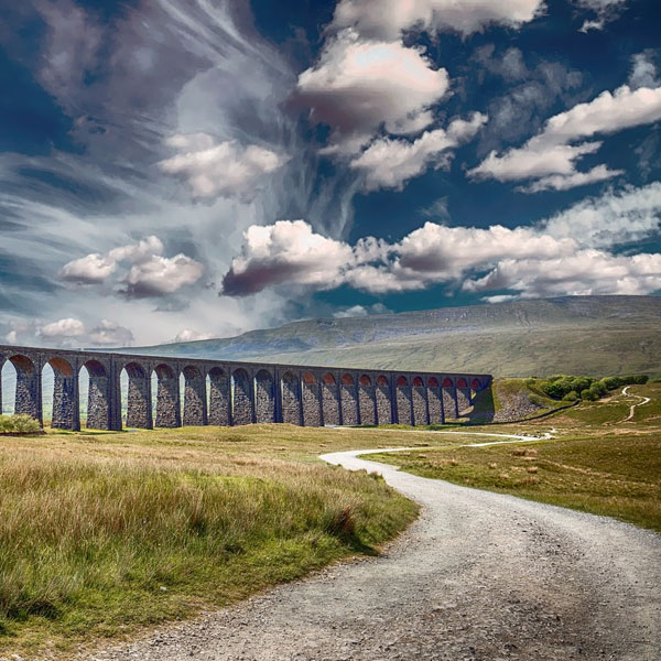 Image of road, grassy field and stone bridge. Meant to illustrate the idea of our Christian spiritual journey